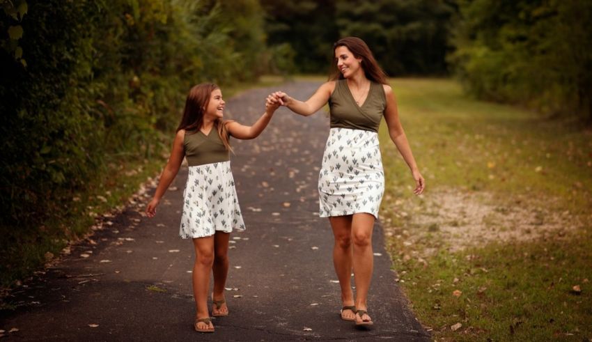A mother and daughter holding hands while walking down a path.