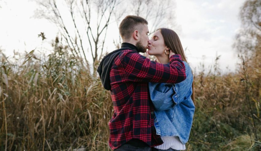 A couple kissing in a field of reeds.