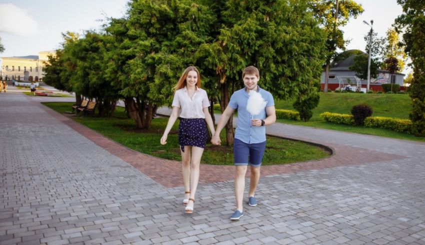A young couple walking down a brick walkway in a park.