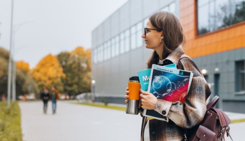 A young woman walking down a street with a backpack and books.