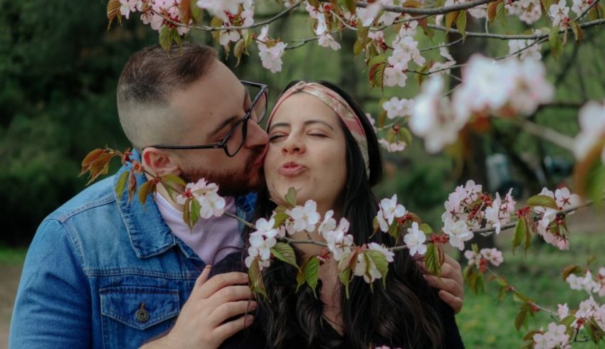 A couple kissing under a cherry blossom tree.