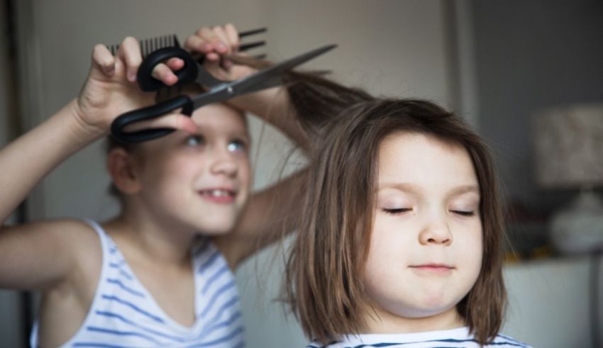 A little girl is getting her hair cut by a pair of scissors.