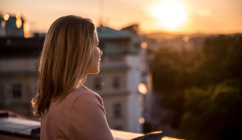 A young woman looking out over the city at sunset.