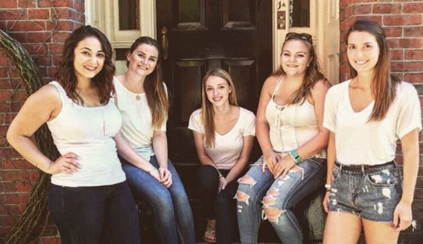 A group of young women posing in front of a house.