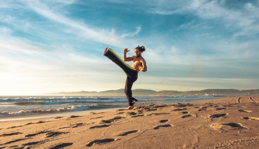 A woman is doing kick boxing on the beach.