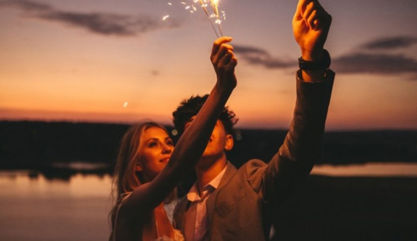 A bride and groom holding sparklers at sunset.
