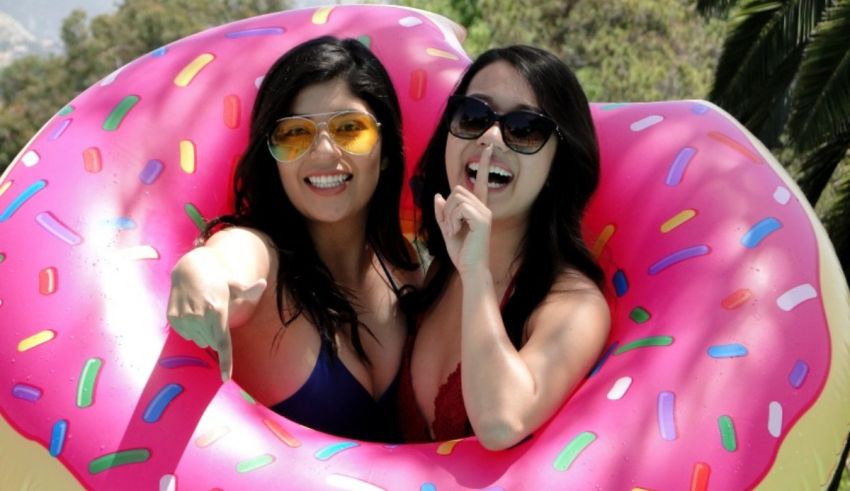 Two women posing in a donut shaped pool float.