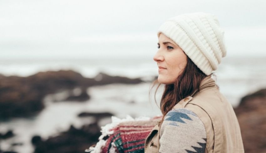 A woman wearing a beanie looking at the ocean.