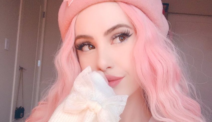 A woman with pink hair wearing a hat and mittens.