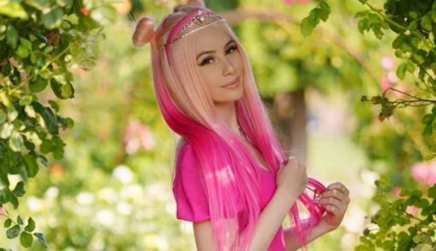 A girl with pink hair posing in a garden.