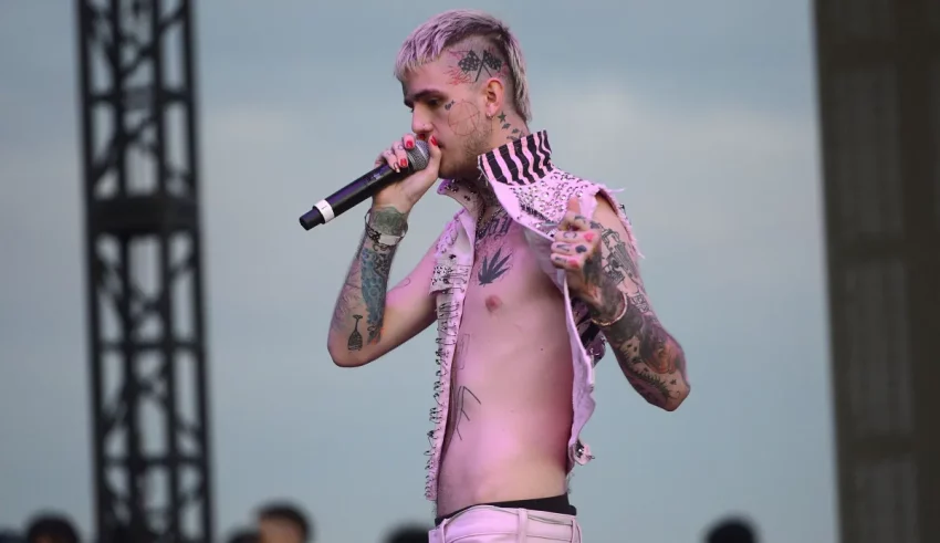 A man with tattoos singing into a microphone.