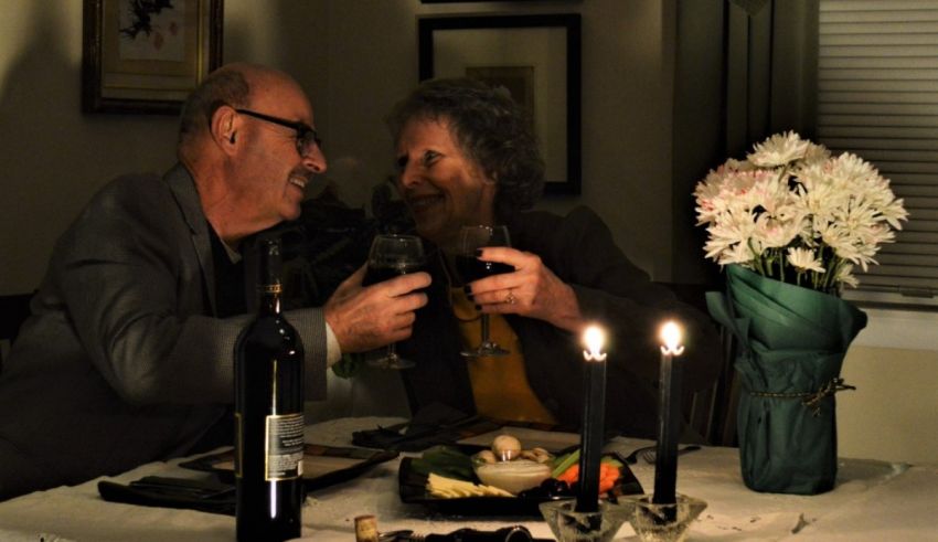 A couple toasts at a dinner table with wine and candles.