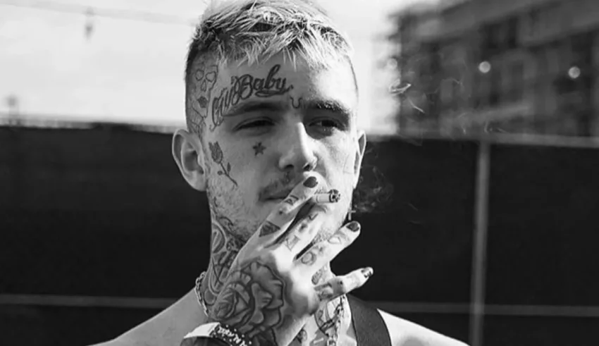 A man with tattoos is smoking a cigarette.