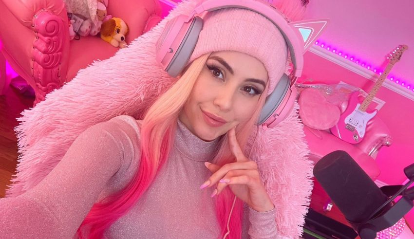 A girl with pink hair and headphones is posing in a pink room.