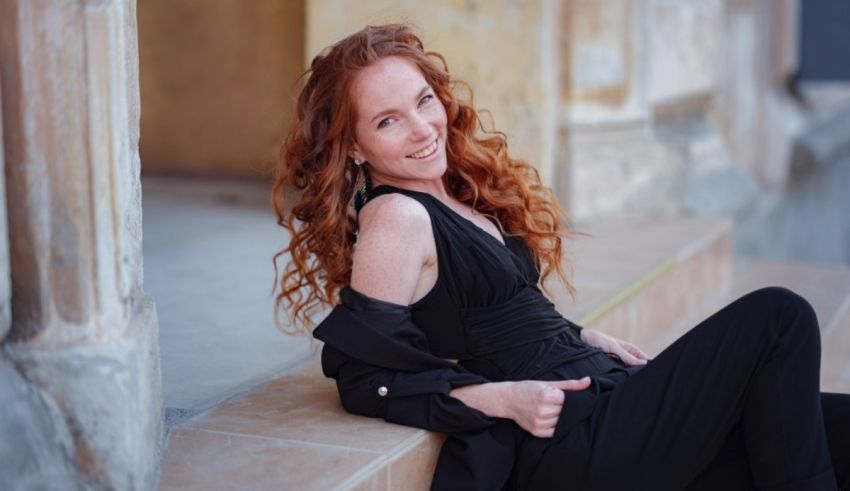 A woman with red hair sitting on steps.