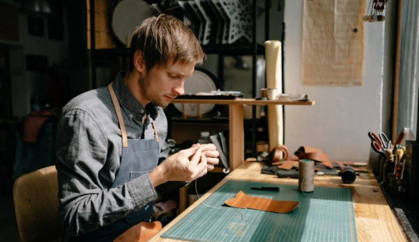 A man in a apron is working on a piece of leather.