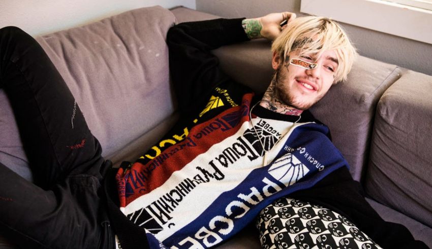 A young man laying on a couch with tattoos.
