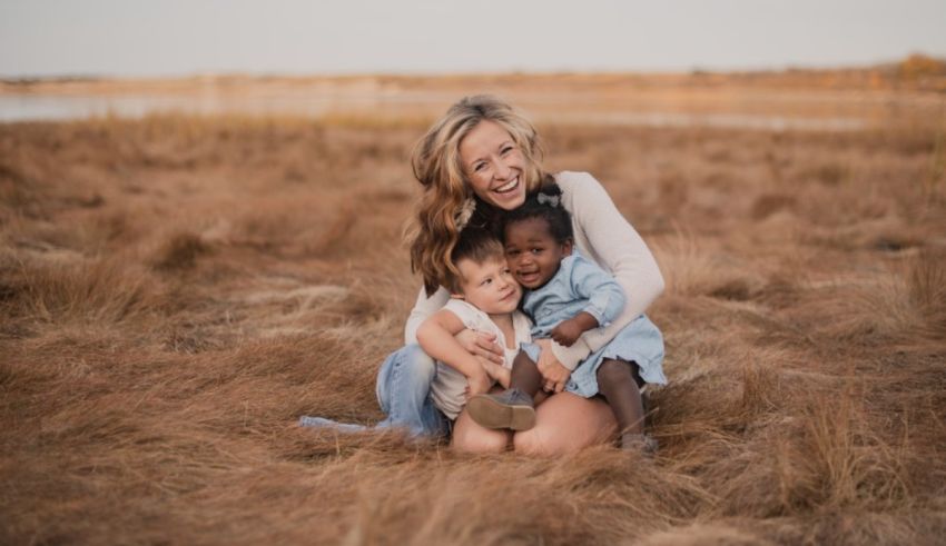 A woman and her children are sitting in a field of tall grass.