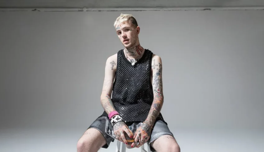 A man with tattoos sitting on a stool.
