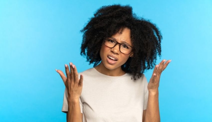 A black woman with afro hair is making a gesture against a blue background.