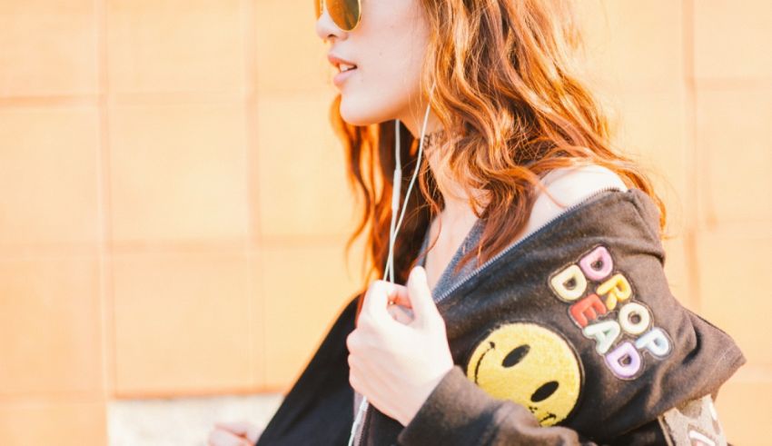 A woman wearing sunglasses and a smiley face hoodie.