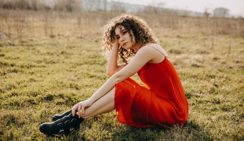 A woman in a red dress sitting in a field.