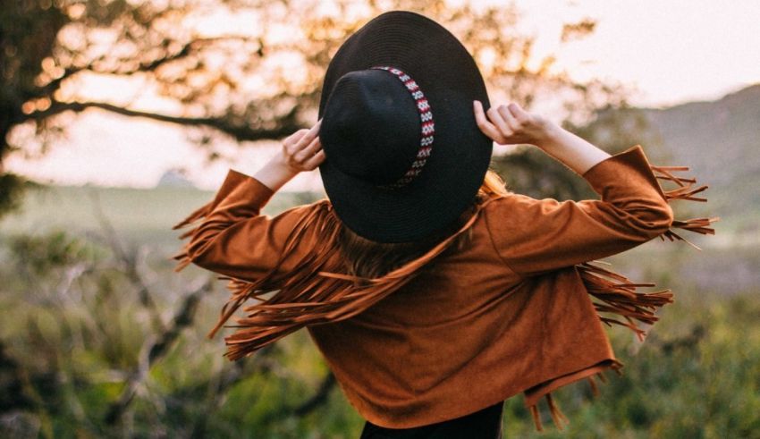 A woman wearing a hat and jacket in a field.