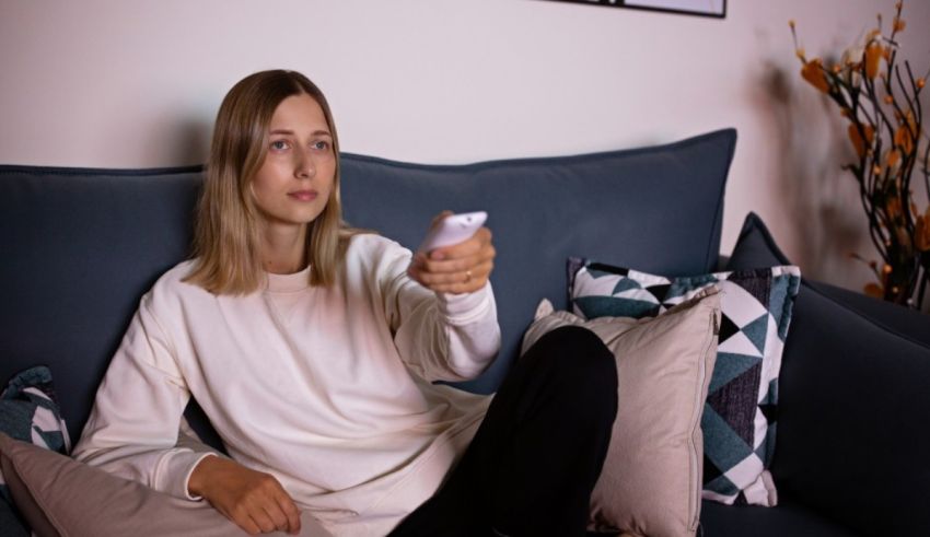 A woman sitting on a couch holding a remote control.