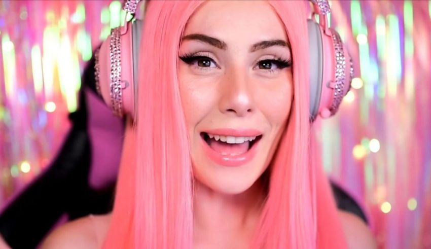 A girl with pink hair and headphones is smiling.