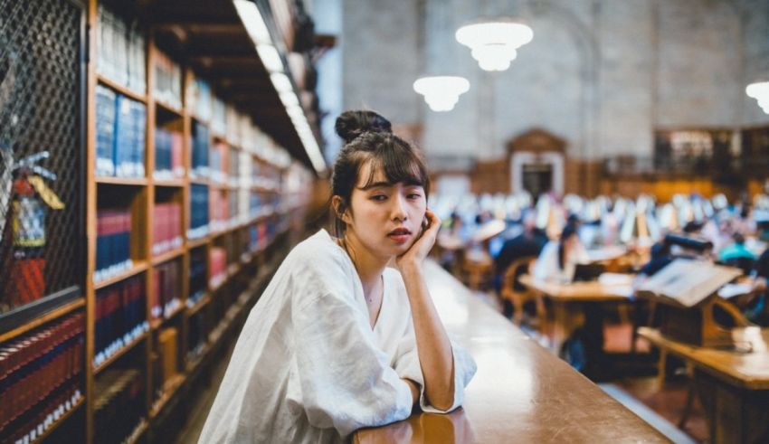 A young woman sitting at a table in a library.