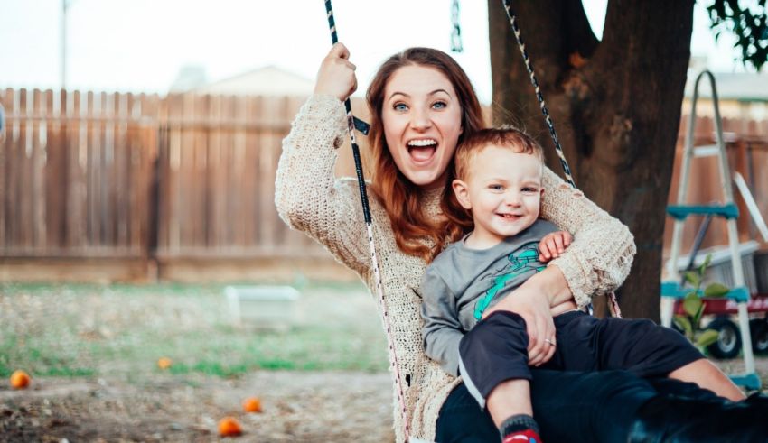 A woman sitting on a swing with her son.