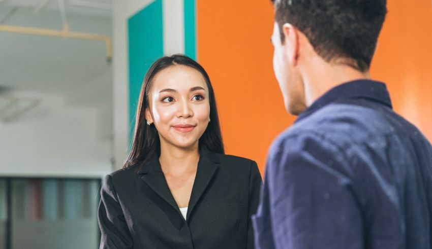 Asian business woman talking to a man in an office.