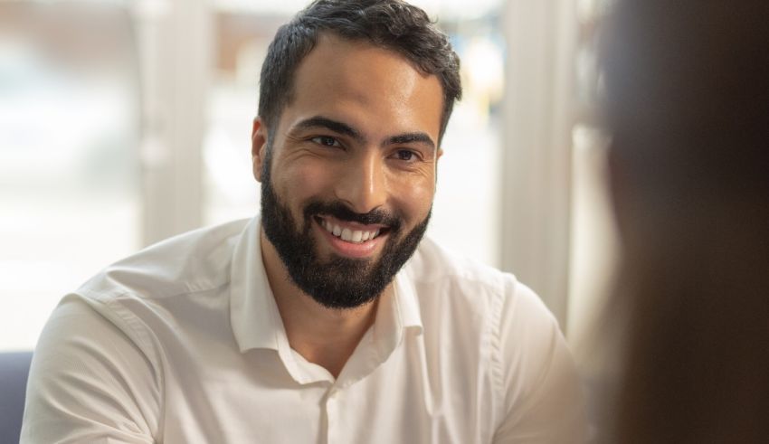 A man with a beard smiling at a woman in an office.