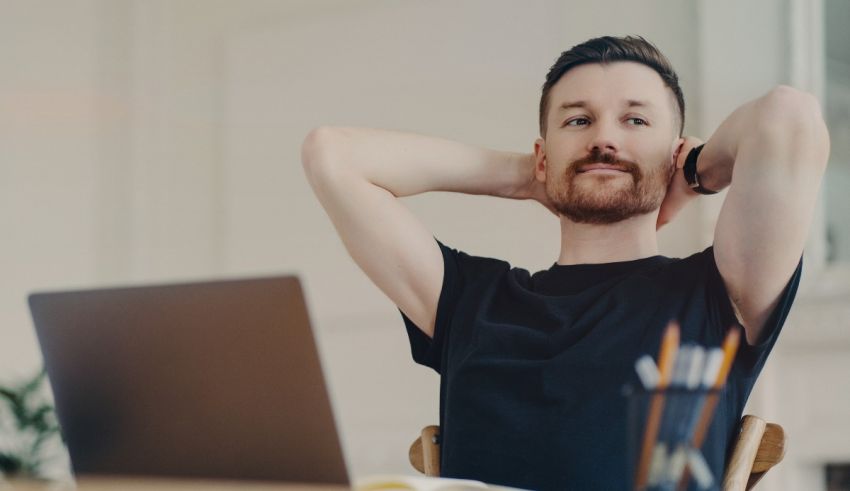 A man sitting at a desk with his hands on his head.