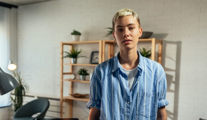 A woman in a blue shirt standing in front of a desk.