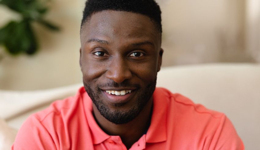 A black man smiling in a pink shirt.