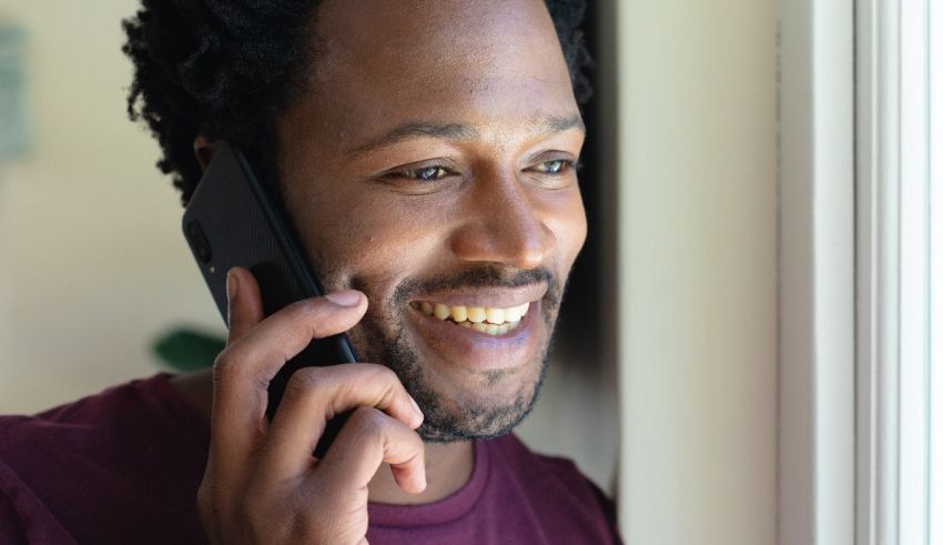 A man smiling while talking on a cell phone.