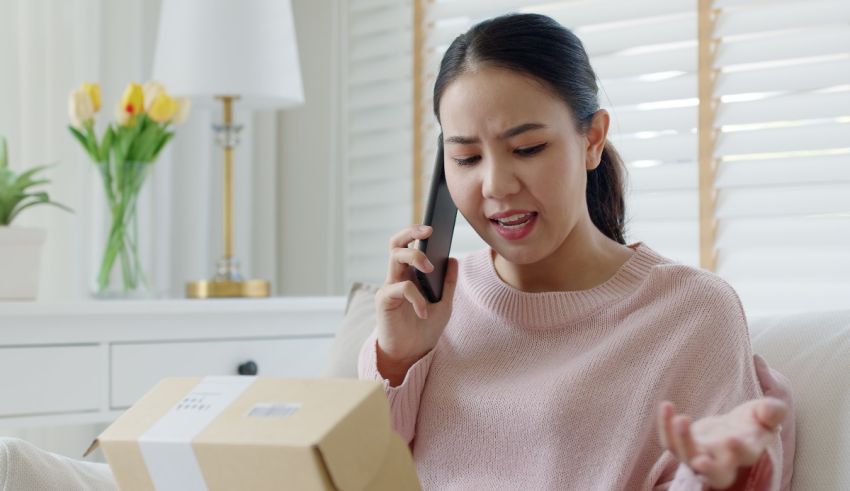 Asian woman talking on the phone while holding a package.