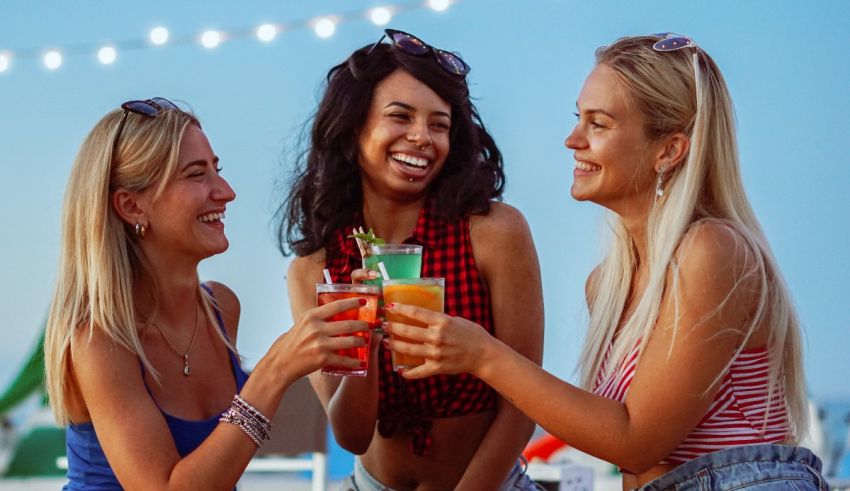 A group of women drinking cocktails on a beach.