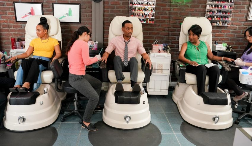 A group of people sitting in chairs at a nail salon.