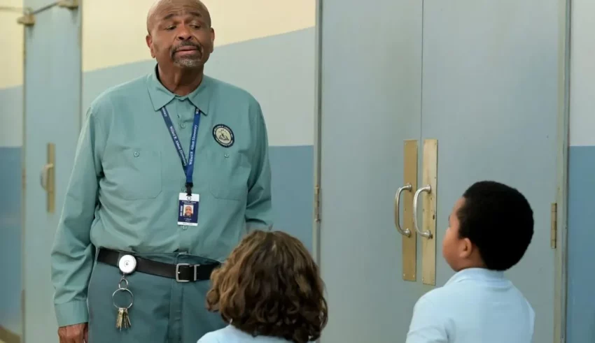 A man talking to a group of children in a hallway.