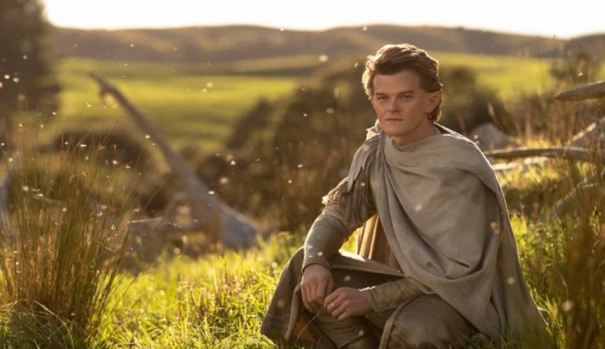 A man in a cloak sitting in a field.