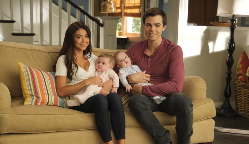 A man and woman sitting on a couch with two babies.