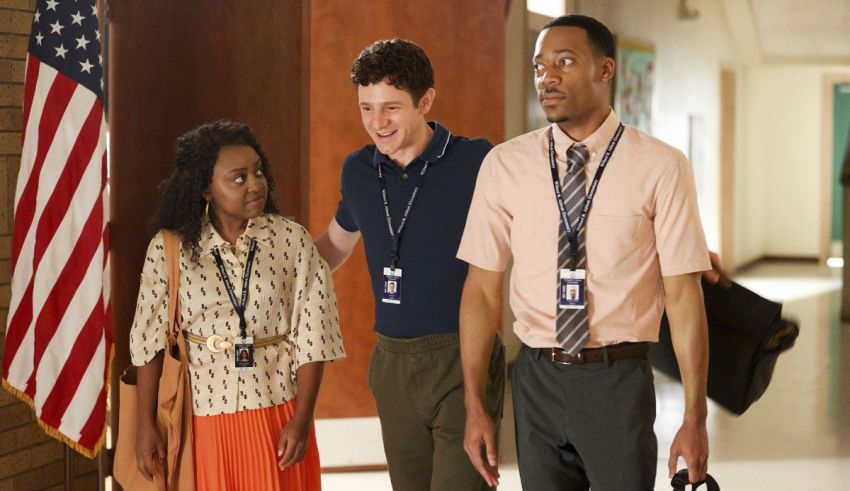 Three people standing in a hallway with an american flag.