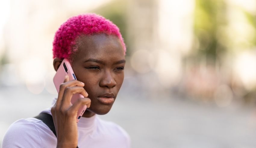 A woman with pink hair talking on a cell phone.