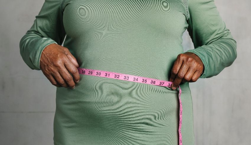 A pregnant woman is holding a measuring tape.