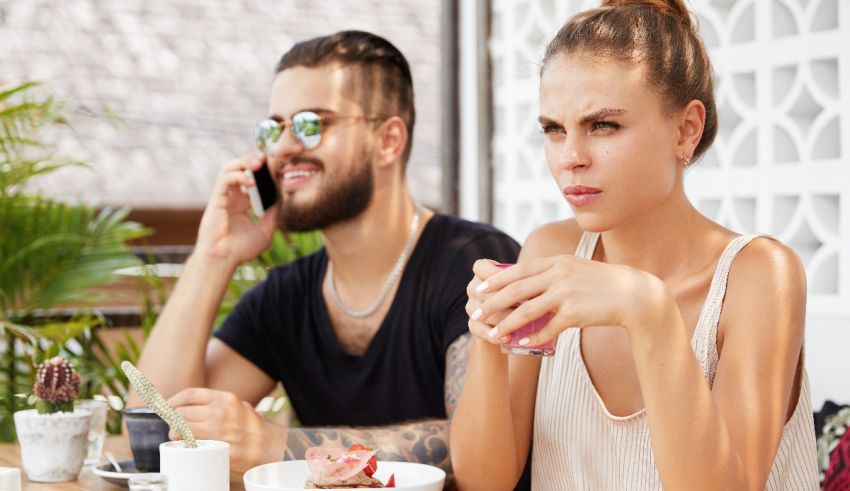 A man and woman sitting at a table and talking on the phone.