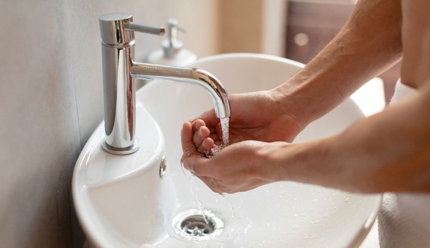 A man washing his hands in a bathroom sink.