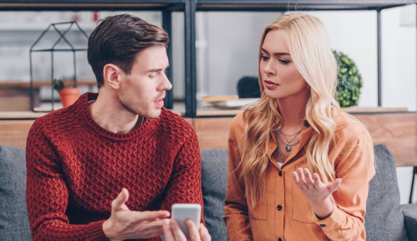 A man and woman sitting on a couch talking to each other.