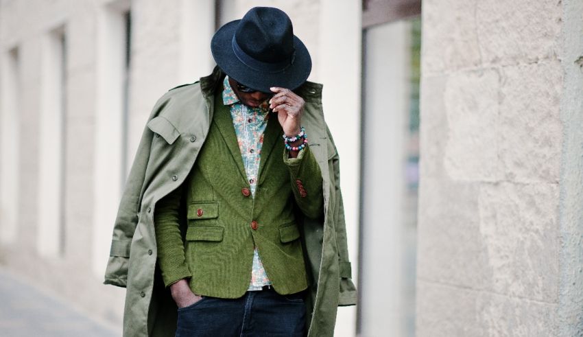 A man in a green jacket and hat is talking on the phone.